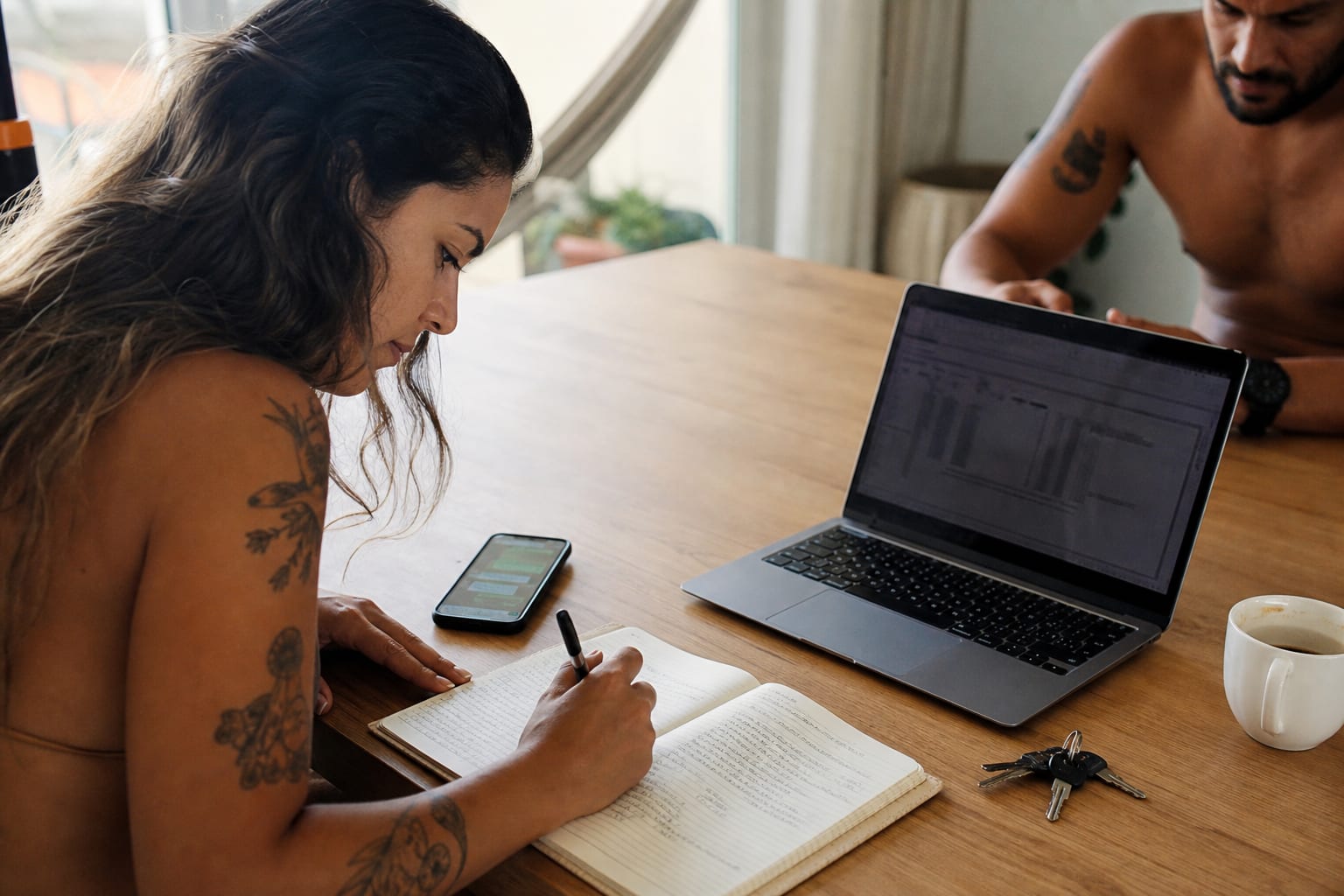 Mesa com caderno, celular e notebook usados para coordenar faxinas de temporada